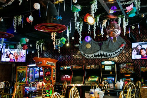 Colorful arcade interior with games, hanging decorations, and a large shark mural on the wall.