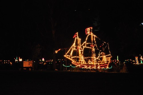 A brightly lit pirate ship made of Christmas lights, set against a dark night sky.