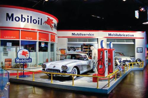 Vintage Mobil oil station display featuring classic cars, gas pumps, and service areas. Retro decor and signage.