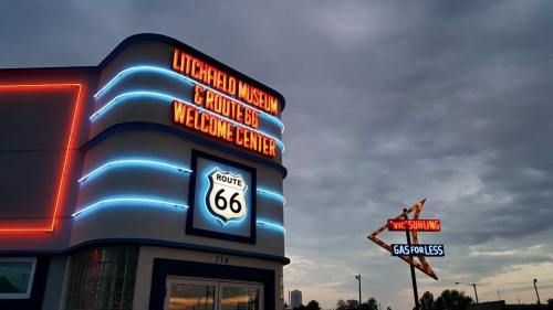 Signage for Litchfield Museum and Route 66 Welcome Center, featuring neon lights and a retro gas station sign.