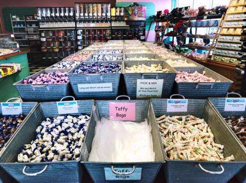 A colorful display of assorted taffy in metal bins, with a "Pick & Mix" sign in a vibrant candy shop.