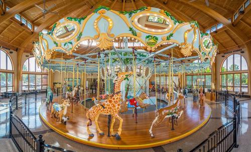 A colorful carousel featuring intricately designed animal figures, including giraffes, in a spacious, well-lit building.
