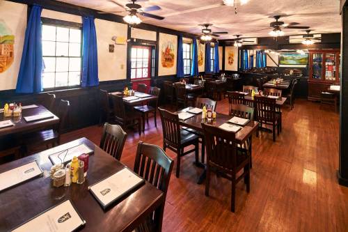 Cozy restaurant interior with wooden tables, chairs, and blue curtains, featuring a warm, inviting atmosphere.