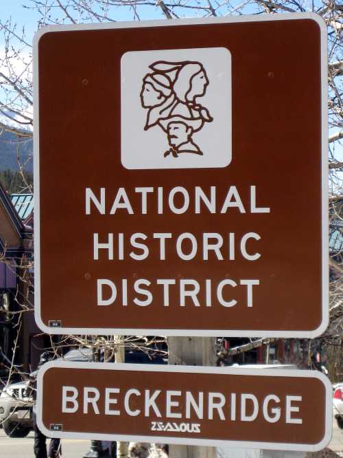 Sign for the National Historic District in Breckenridge, featuring a graphic of faces and text in white on a brown background.