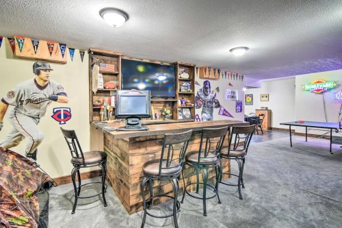 A cozy game room featuring a bar, sports memorabilia, a large TV, and a ping pong table.