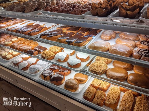 A display case filled with various donuts, including glazed, chocolate-covered, and nut-topped varieties.