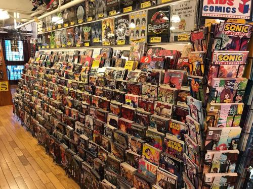 A colorful display of comic books arranged on shelves in a store, featuring various titles and genres.