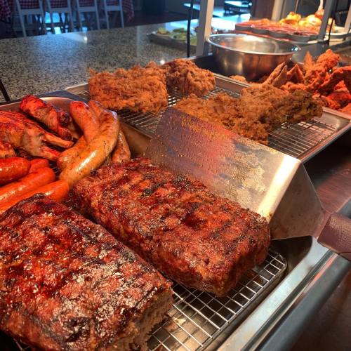A variety of grilled meats including ribs, sausages, and fried chicken displayed on a buffet table.