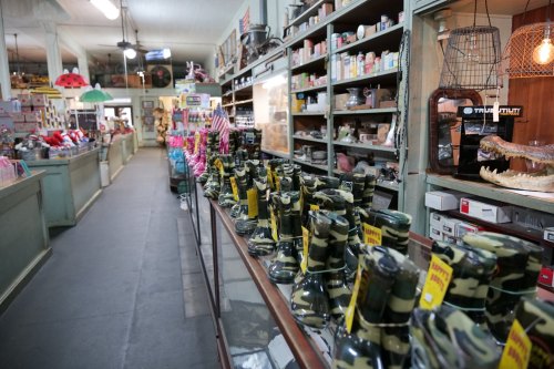 A vintage store aisle lined with camo-patterned boots and various nostalgic items on shelves.