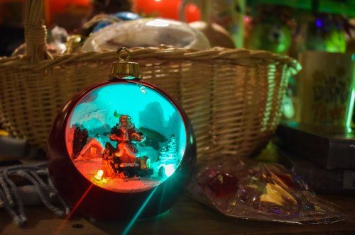 A festive snow globe featuring a Santa figure, illuminated with colorful lights, surrounded by holiday decorations.