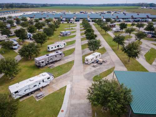 Aerial view of an RV park with multiple parked RVs and tree-lined pathways in a green landscape.