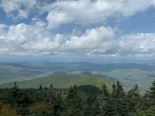A panoramic view of lush green mountains under a partly cloudy sky.