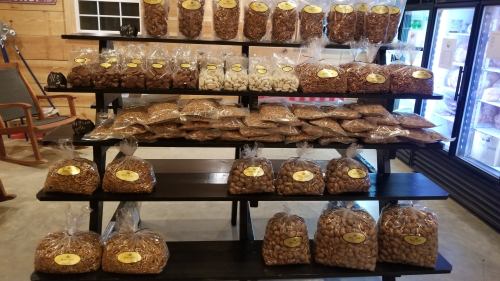 A display of various bags of nuts arranged on wooden shelves in a store.