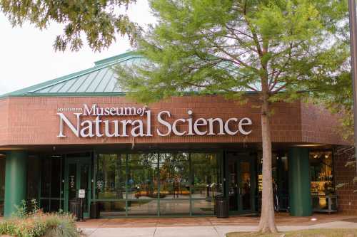 Exterior view of the Mississippi Museum of Natural Science, featuring a green roof and large glass entrance.