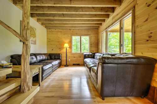 Cozy living room with wooden beams, leather sofas, and large windows letting in natural light.