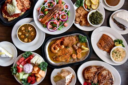 A variety of dishes including pasta, seafood, salad, and fruit arranged on a table.