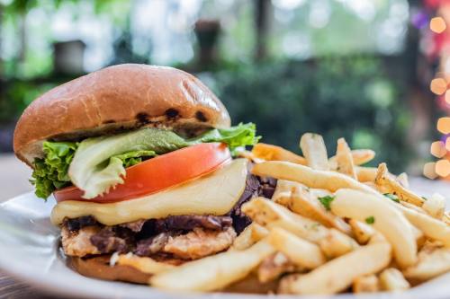 A juicy burger with lettuce, tomato, and cheese, served with a side of crispy fries on a plate.