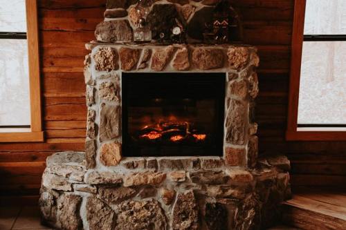 A cozy stone fireplace with glowing embers, set against a rustic wooden wall.