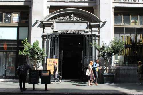 A historic building entrance with ornate architecture, featuring people outside and a sign for "The Last Bookstore."