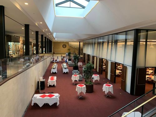 A spacious restaurant interior with tables set for dining, large windows, and a skylight overhead.