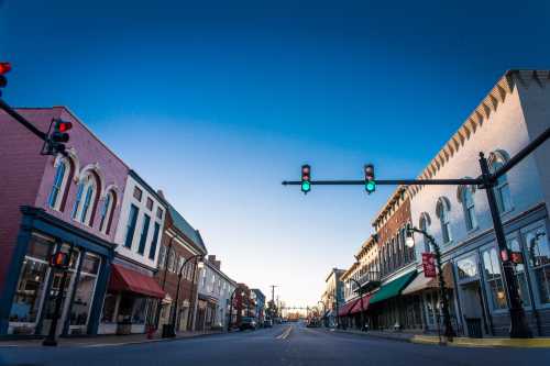 A quiet street in a small town, featuring historic buildings and traffic lights showing green against a clear blue sky.