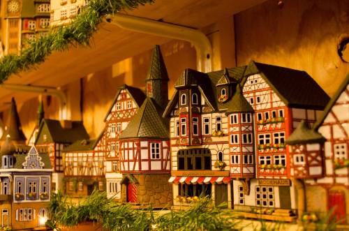 A close-up of colorful miniature buildings on a shelf, decorated with greenery for a festive atmosphere.