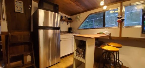 A cozy kitchen with stainless steel appliances, wooden accents, and a small dining area with bar stools.