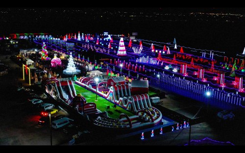 Aerial view of a vibrant holiday light display with inflatable attractions and festive decorations.