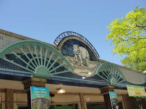 Sign for Roger Williams Park Zoo, featuring decorative elements and a clear blue sky above.