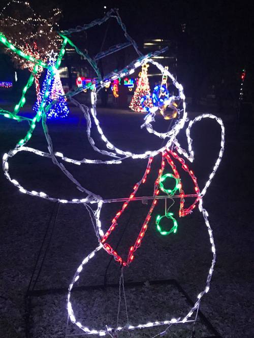 A glowing snowman made of lights, wearing a red scarf and green buttons, surrounded by colorful holiday decorations.
