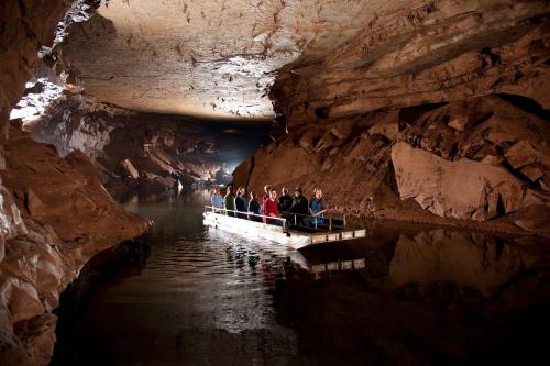 A group of people on a boat exploring a dark cave with rocky walls and water reflecting the dim light.