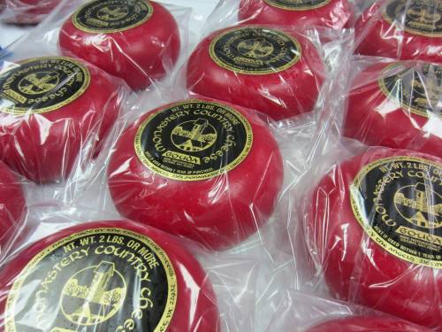 Red wax-covered cheese wheels with black labels, arranged neatly in a display.