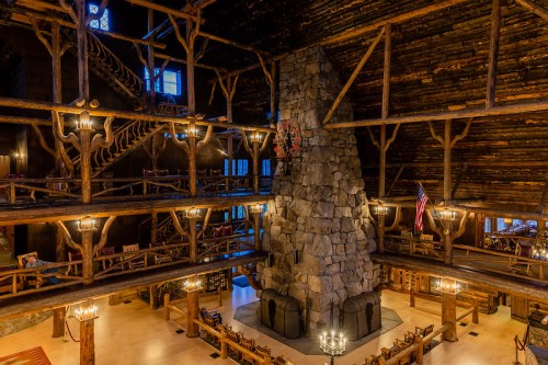 A spacious lodge interior featuring a large stone fireplace, wooden beams, and multiple levels with rustic decor.