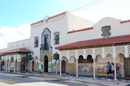 Colorful building with intricate tile work and arched windows, featuring a red-tiled roof and a clear blue sky.