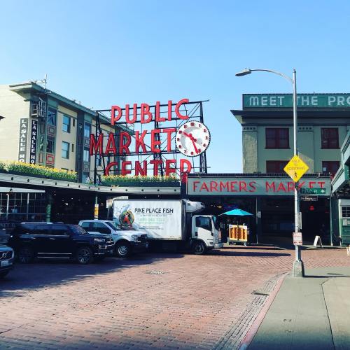 A bustling market scene featuring the iconic Public Market Center sign and a farmers market entrance.