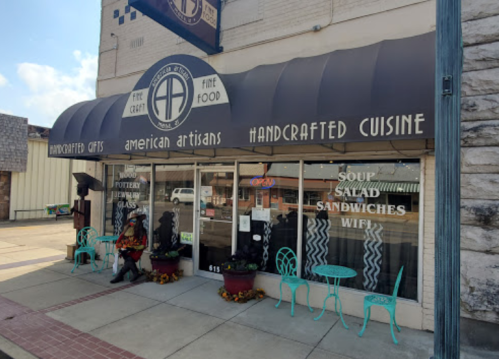 A storefront with a blue awning displaying "Handcrafted Cuisine" and signs for soup, salad, and sandwiches.