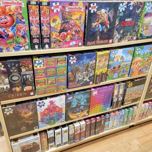 A colorful display of various puzzle boxes, including themes like cartoons, music, and video games on wooden shelves.