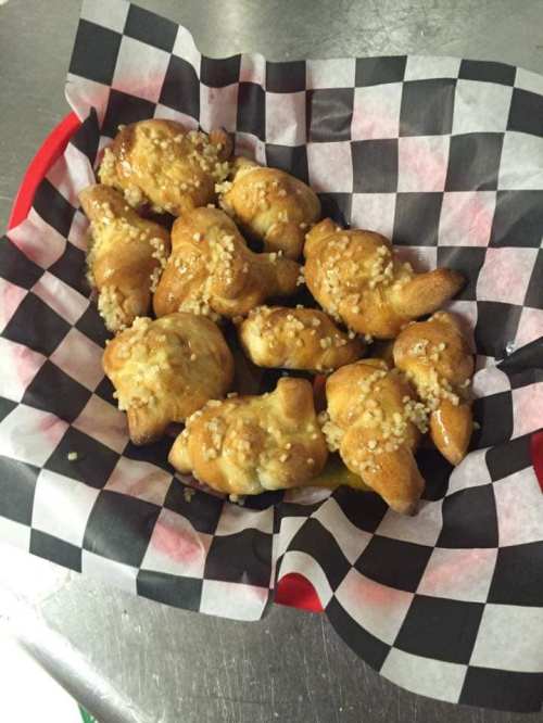 A basket of golden-brown, sesame-topped dough bites on a checkered paper liner.