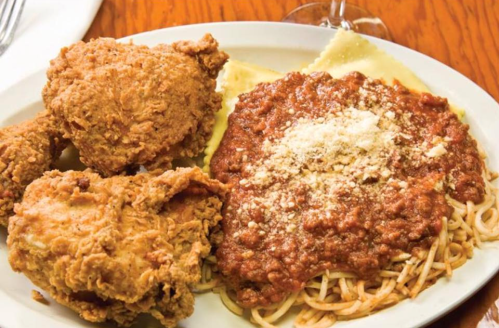A plate featuring fried chicken, spaghetti with meat sauce, and ravioli topped with cheese.