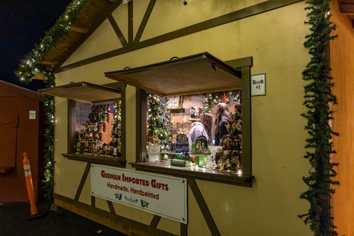 A festive market stall decorated with lights, showcasing handmade German gifts and ornaments.