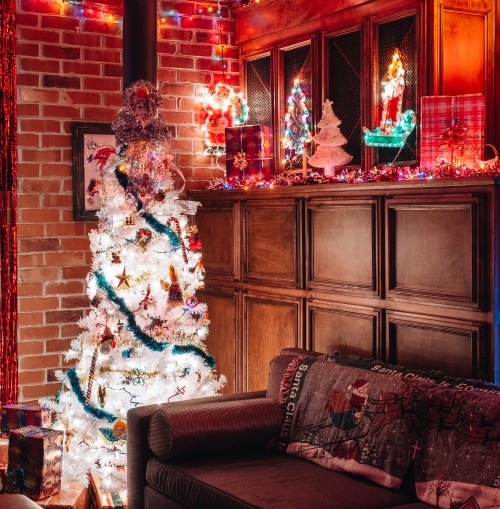 A cozy room decorated for Christmas, featuring a white tree, colorful lights, and festive ornaments.