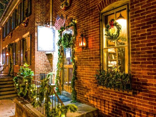 A brick building adorned with festive wreaths and greenery, illuminated by warm lights during the holiday season.