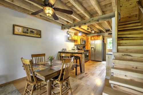 Cozy kitchen and dining area with wooden furniture, a ceiling fan, and stairs leading to an upper level.