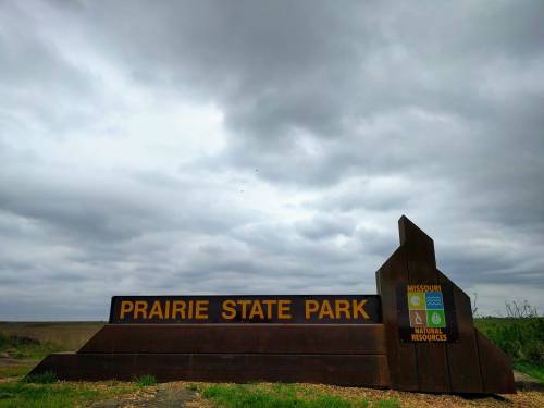 Sign for Prairie State Park against a cloudy sky, featuring logos for Missouri and Natural Resources.