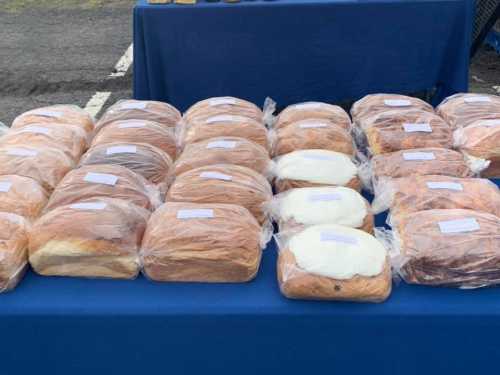 A table covered with loaves of bread, some wrapped in plastic, arranged neatly in rows.