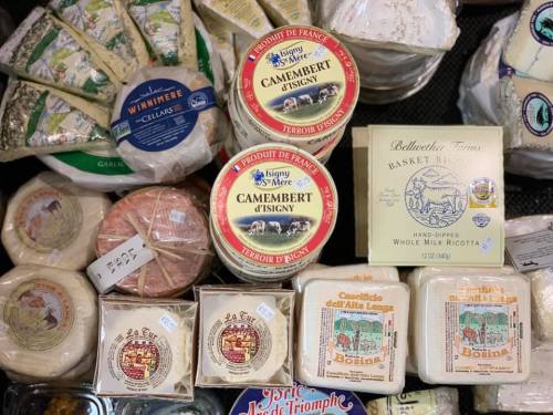 A variety of cheeses displayed, including Camembert, ricotta, and other artisanal cheese varieties in circular packaging.