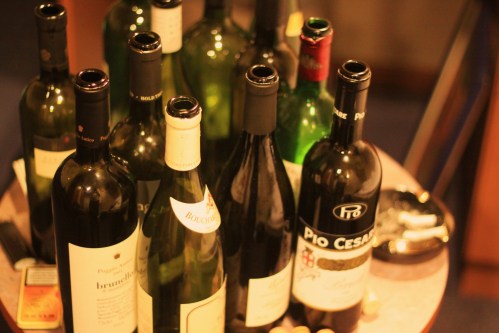 A collection of empty wine bottles on a table, with a few corks scattered around.