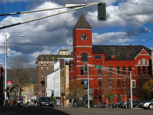 Historic red brick building with a clock tower, streetlights, and a cloudy sky in the background.