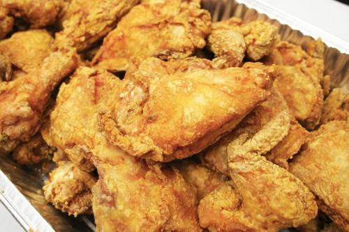 A close-up of a tray filled with golden-brown, crispy fried chicken pieces.