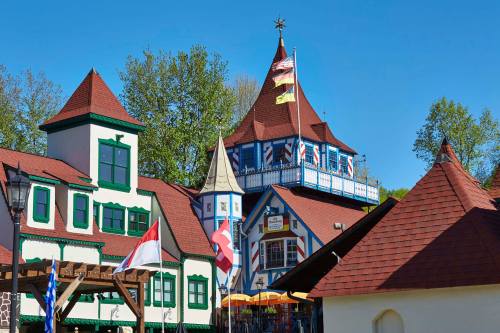 Colorful buildings with unique architecture and flags, set against a clear blue sky and green trees.